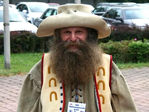 A man with a beard, a hat and some upside-down horseshoes