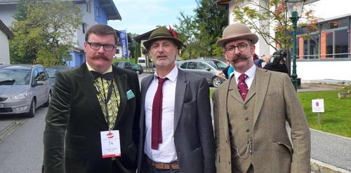 Members Ryan Pike and Allan Robinson flanking Antoine De Caunes, posing for photographs pre-competition.